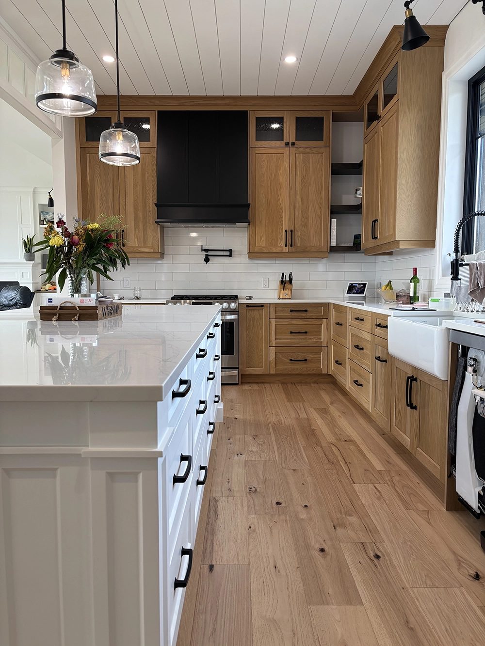 A kitchen with natural wood cabinets and a black range hood